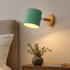 Modern cylindrical wall light beside a bed