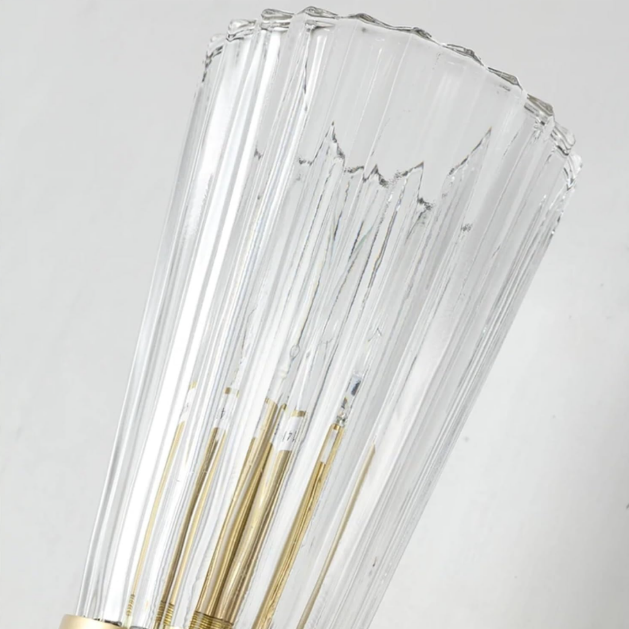 Close-up of the decorative glass shade on the gold wall sconce