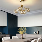 Modern Nordic copper pendant chandelier with amber glass above a dining table