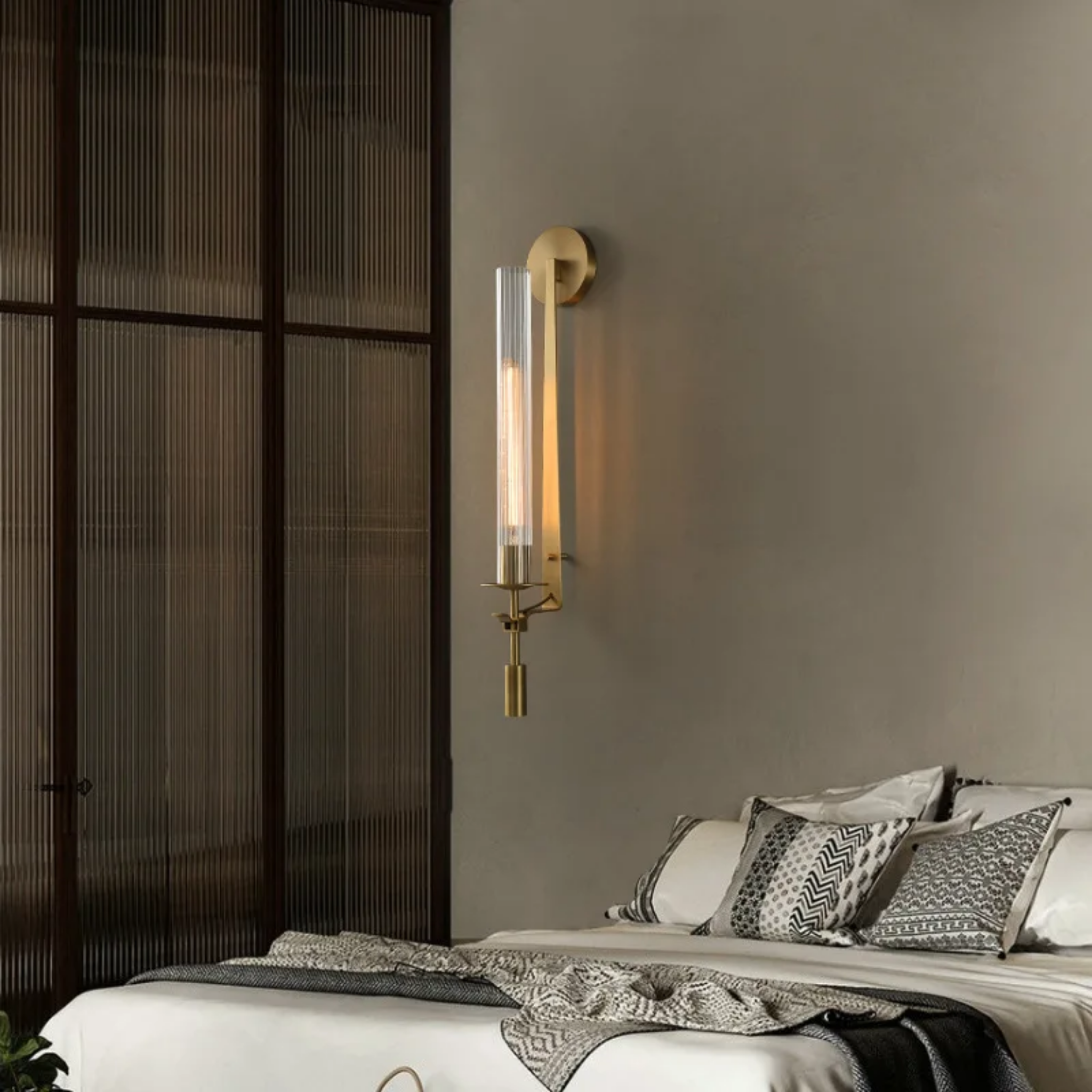 Clear glass wall sconce beside a bed
